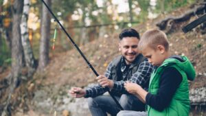 A father and son enjoy fishing together outdoors.