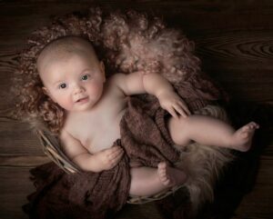 baby lying on brown textile