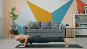 Woman doing a push-up on a yoga mat indoors.